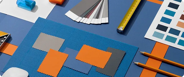 Colour swatches and paper samples in orange, blue and grey on a desk